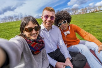 Three cheerful multi ethnic friends are taking a selfie in a park, enjoying a sunny day together
