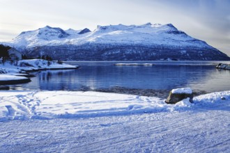 Snowy coastal landscape with mountains by the water, Strávnjunnje, Innhavet, Norway, Europe