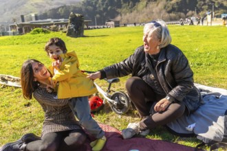 Mother and grandmother having fun with their child in a park, enjoying a sunny day outdoors