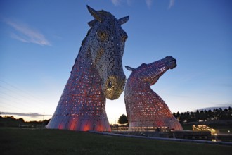 Large illuminated horse sculptures at dusk against the evening sky, legends and myths, Kelpies,