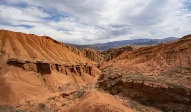 Eroded mountain landscape with sandstone cliffs, canyon with red and orange rock formations,