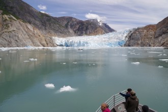 Small boat approaching the front of a glacier calving into the sea, Tracy Arm Fiord, Tongass