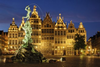 Antwerp famous Brabo statue and fountain on Grote Markt square illuminated at night and old houses.