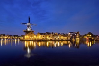 View of Harlem cityscape with landmark windmill De Adriaan on Spaarne river in the night