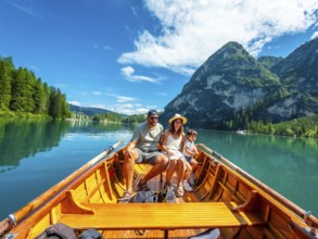 Family enjoying a sunny summer day rowing a wooden boat on the crystal clear waters of lake braies,