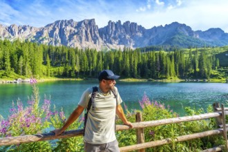 Hiker admiring the stunning landscape of lake carezza with the latemar mountain range in the