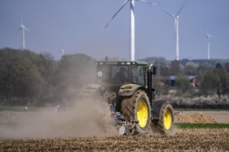 A tractor works a field, due to long dryness in spring, no rain for more than 4 weeks, the fields