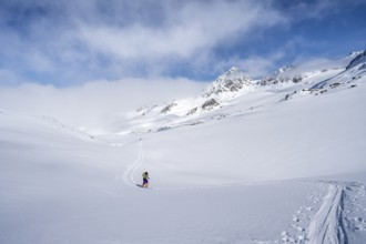 Ski tourer ascending through a picturesque snow-covered mountain landscape with views of mountain