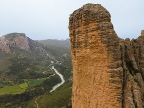 View of a huge rock, a valley with a river below and an impressive natural backdrop, aerial view,