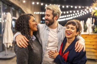 Happy multi-ethnic coworkers embracing while celebrating party in a bar terrace outdoors after work