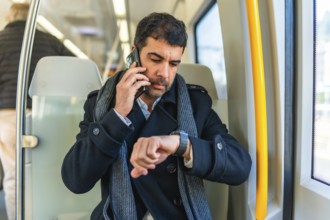 Adult caucasian businessman talking to the mobile phone and checking the time while commuting with