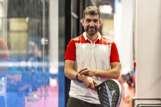 Smiling mature man playing with paddle tennis racket in an indoor court
