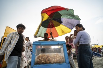 GUWAHATI, INDIA - APRIL 5: A vendor sells panipuri as he stand under a large umbrella during a pre