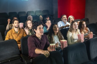 People are watching a movie and eating popcorn in a movie theater, enjoying the show together