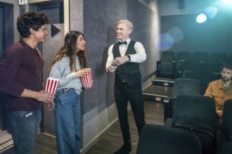 Couple holding popcorn buckets giving their tickets to the usher before entering the movie theater