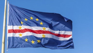 The flag of Cape Verde flutters in the wind, isolated against a blue sky