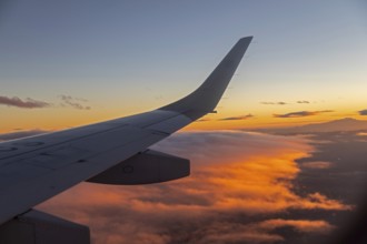 Mexico City, An AeroMexico Connect Embraer jet flies over orange clouds as it approaches Mexico
