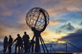Tourists in front of the steel globe at the North Cape in the evening light, Nordkapp, Finnmark,