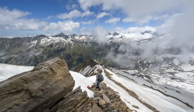Mountaineer on a rocky ridge with snow, descent from the summit of Schönbichler Horn, view of