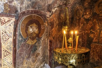 Candlelit orthodox wall painting in a dark, mystical setting, icon depicting Christ, church of Agia