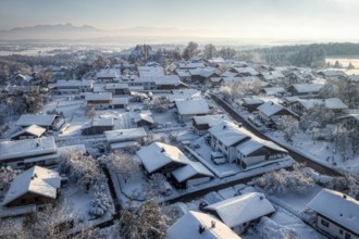 A snow-covered village in a wintry landscape with a blue-white sky and a peaceful atmosphere,