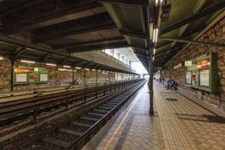 People sitting on a historic platform next to the underground railway tracks, Vienna