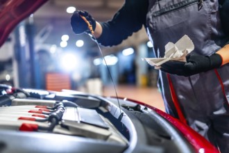 Female car mechanic checking the oil level of a car engine during a maintenance service in a
