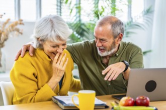 Senior woman looking at household finances notes and expressing surprise and happiness while her