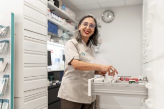 Side view photo of a woman cheerful pharmacist smiling while working in the storage room