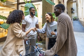 Women shaking hands at the entrance of a modern coworking standing next to multiracial colleagues