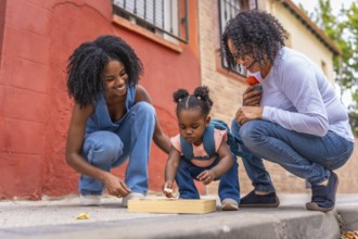 Multi-generation african woman playing with girl and toys in the street