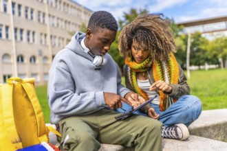 Students addicted to technology and the internet sitting outside the campus using digital tablet