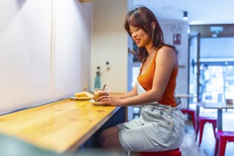 Side view portrait with copy space of a happy chinese cool woman drinking coffee in a cafeteria