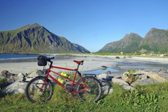 A bicycle on the beach with a view of the surrounding mountains and the sea, Flakstad, Lofoten,