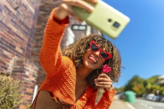 Young and vital latin woman taking selfie while eating lollipop outdoors