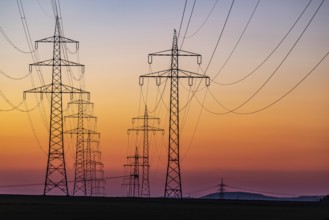 High-voltage pylons, overhead power lines at sunset. Schwieberdingen, Baden-Württemberg, Germany,