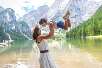 Happy mother lifting her son, enjoying summer vacation at lake braies - pragser wildsee - in the