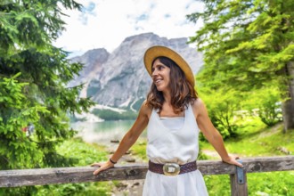 Woman wearing straw hat enjoying the landscape at lake braies, also called pragser wildsee, during