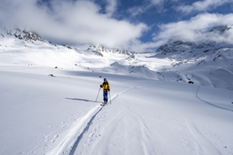 Ski tourer ascending through picturesque snow-covered mountain landscape with views of mountain