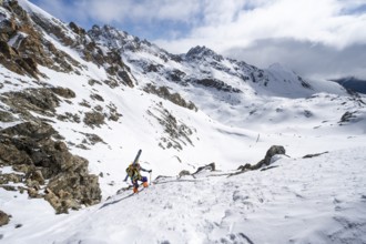 Mountaineer with skis climbing up a steep snow slope to the fork Porta d'Es-cha, ski tour Bündner