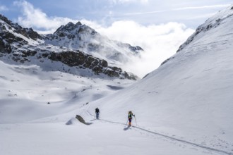 Atmospheric clouds in a wintry mountain landscape, ski tourers on the ascent to Porta d'Es-cha,