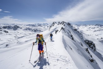Two ski tourers on a mountain ridge, mountain landscape with snow, mountain panorama with peaks of