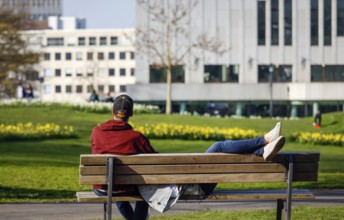 A couple relaxing on a park bench in the city garden in times of the corona crisis, Essen, Ruhr