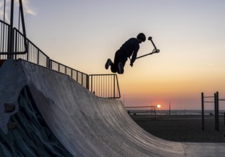 Skater, scooter in a halfpipe at the beach of Scheveningen, sunset, Netherlands