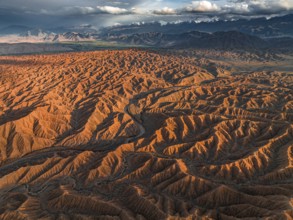 Landscape of eroded hills, badlands at sunset, mountain peaks of the Tian Shan Mountains in the