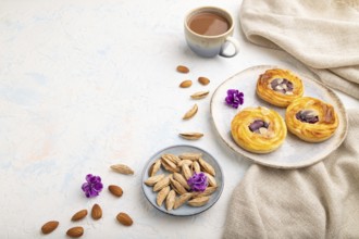 Small cheesecakes with jam and almonds with cup of coffee on a white concrete background and linen