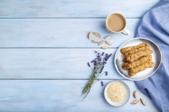 Crumble cookies with seasme and almonds on ceramic plate with cup of coffee and blue linen textile