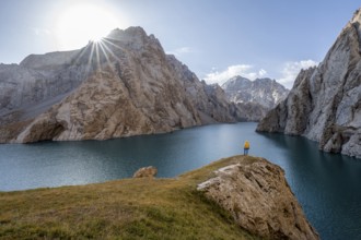 Tourist at the blue mountain lake between rocky steep mountain peaks, Sun Star, Kol Suu Lake, Sary