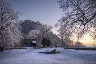 The snow-covered Karlsbastion of the Hohentwiel fortress ruins in front of sunrise on a cold winter