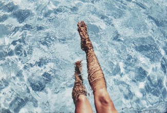 Two legs protrude from the blue pool water, calming beauty